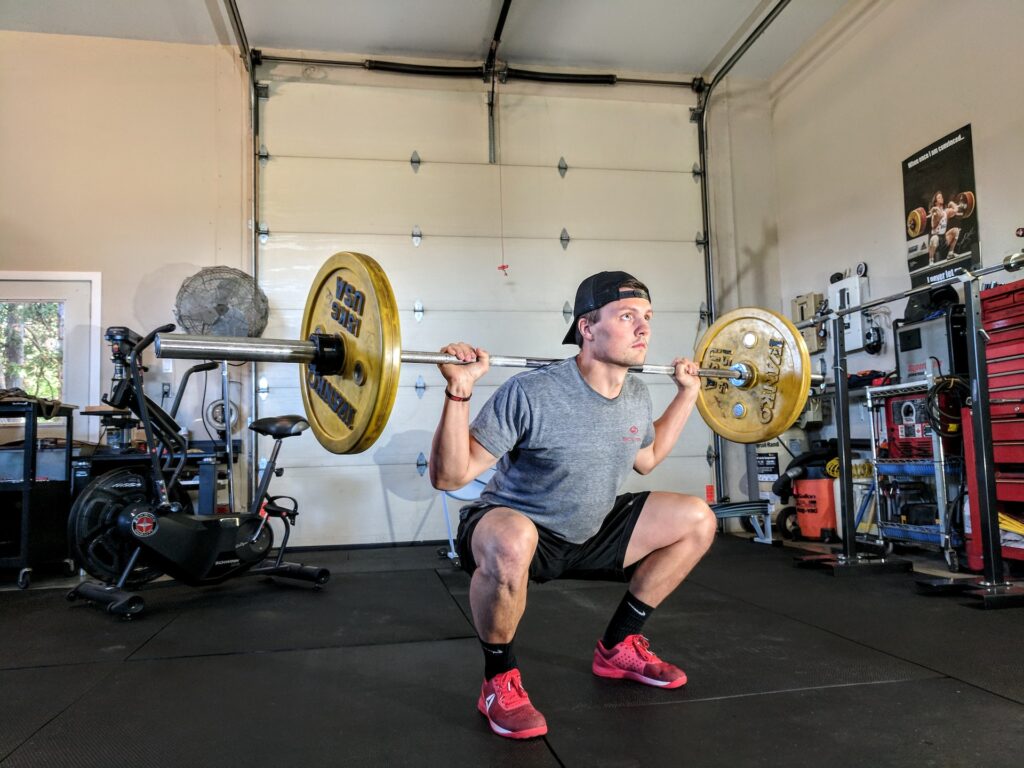 A man doing a 50kg barbell squat in a garage gym demonstrating a controll eccentric rep speed