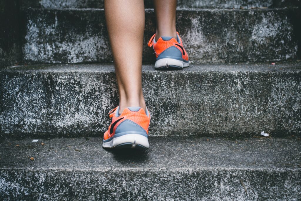 Woman walking up a set of stairs demonstrating daily activity which can aid in fat loss