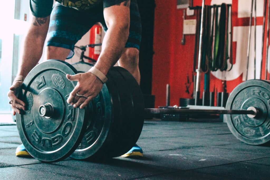 man in the gym placing additional weight onto his bar for warm up sets